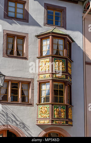 Dettaglio di legno decorato a baia finestra sul vecchio azzurro facciata, girato in condizioni di intensa luce di primavera a Rottweil, Baden Wuttenberg, Germania Foto Stock