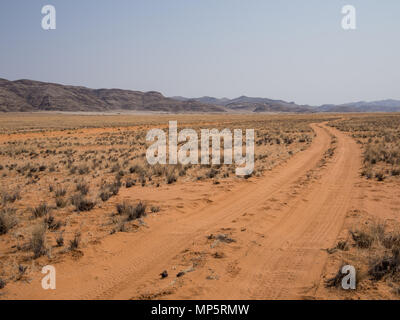 Vuoto Pneumatico via strada sterrata nel deserto del Namib con montagne, Damaraland, Namibia, Sud Africa Foto Stock