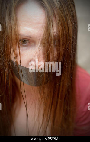 La bocca di una giovane donna sigillato con un nastro adesivo. Il diritto di voto è un problema politico e sociale Foto Stock