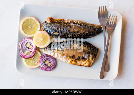 Sgombro pesce con le cipolle e i limoni nella piastra. Concetto di frutti di mare. Foto Stock