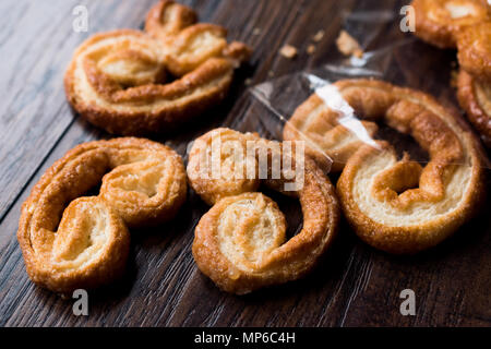 Palmier i cookie nella piastra nera su una superficie di legno. Concetto di dessert. Foto Stock