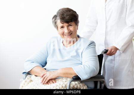 Sorridente senior disabili donna in una sedia a rotelle in casa di riposo Foto Stock