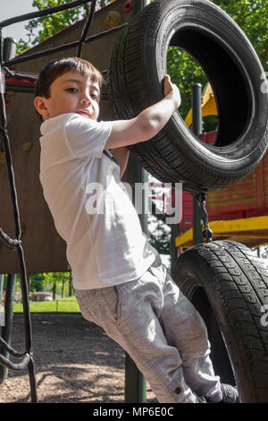 Un giovane ragazzo gioca su un telaio di arrampicata in Prospect Park in Reading, Berkshire, Regno Unito. Foto Stock