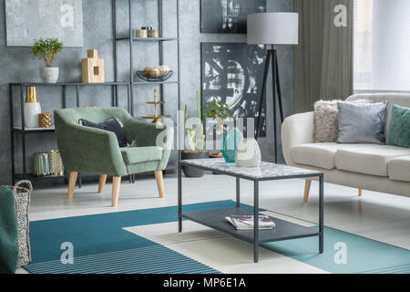 Tabella tra verde poltrona e divano in soggiorno moderno con interni dipinti di nero Foto Stock