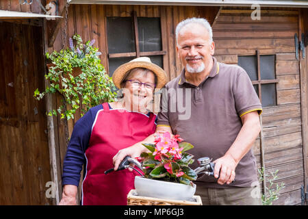 Coppia senior in amore tempo libero insieme all'aperto su una bici in stile vintage sorridente e divertimento sotto il sole delle vacanze. Un modo alternativo di essere ritirato Foto Stock