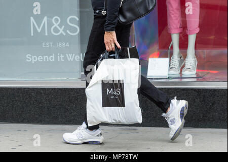 Londra, Regno Unito. 21 Maggio, 2018. Persona in possesso di un sacchetto di plastica passeggiate passato una finestra di Marks & Spencers store a Marble Arch e Oxford Street. La società dovrebbe annunciare ulteriori chiusure di store nel Regno Unito prima del suo reddito annuo annuncio Credito: Raymond codolo/Alamy Live News Foto Stock