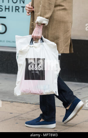 Londra, Regno Unito. 21 Maggio, 2018. Persona in possesso di un sacchetto di plastica passeggiate passato una finestra di Marks & Spencers store a Marble Arch e Oxford Street. La società dovrebbe annunciare ulteriori chiusure di store nel Regno Unito prima del suo reddito annuo annuncio Credito: Raymond codolo/Alamy Live News Foto Stock