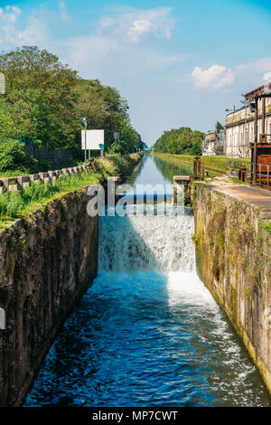 Cascata su una serratura presso il Naviglio Pavese, un canale che collega la città di Milano con Pavia, Italia Foto Stock