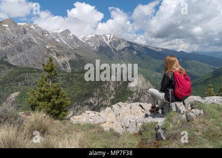Escursionista femmina si prende una pausa e gode di viste sulla montagna, Alpi, Liguria, Italia Foto Stock