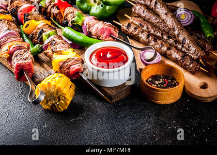 Assortimento vari barbecue grill alimentare carne, barbecue party fest - shish kebab, salsicce, carne alla griglia filetto, verdure fresche, salse, spezie, scuro rusty Foto Stock