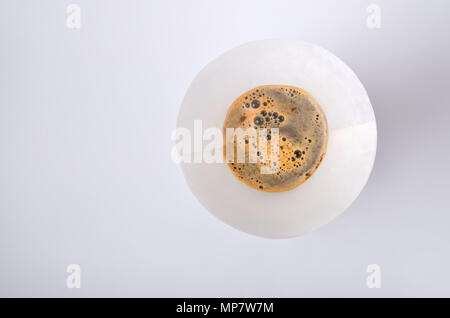 Il filtro di carta con un mix di acqua calda e polvere di caffè nella bevanda vintage maker isolato su sfondo bianco. Parte superiore di vista. Foto Stock