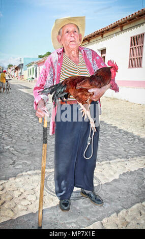 TRINIDAD, CUBA-13 gennaio: Unidentified l'agricoltore che detiene un gallo sulla strada di Trinidad il 13 gennaio. 2010. Trinidad, Cuba. Lavoro nel turismo è t Foto Stock