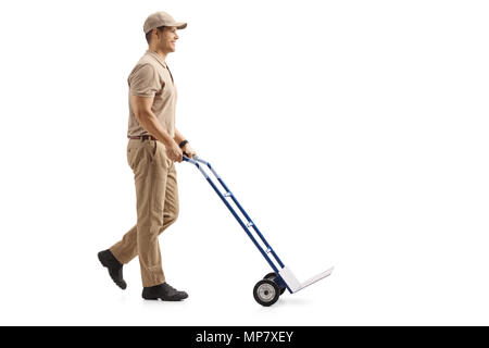Lunghezza piena ripresa di profilo di un uomo di consegna spingendo una mano Vuota carrello isolato su sfondo bianco Foto Stock