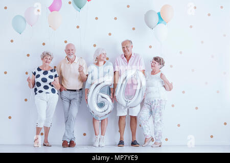 Felici le persone anziane azienda palloncini durante una festa di compleanno Foto Stock