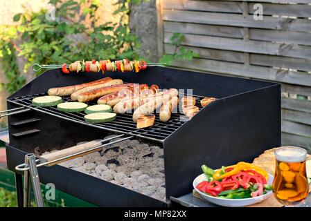 Il cibo era gustoso, nutrizione, della cucina e del barbecue concetto: salsicce alla griglia,spiedini,la zucchina e baguette su un barbeque. Foto Stock