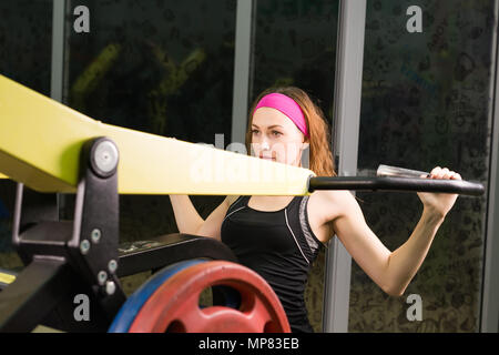 Donna fitness esecuzione di esercizio con la macchina ginnica in palestra Foto Stock