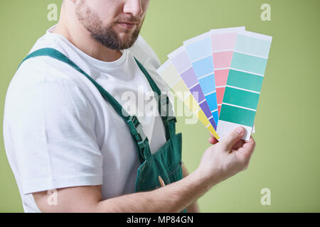 Giovane pittore in uniforme tenendo la tavolozza dei colori delle vernici Foto Stock