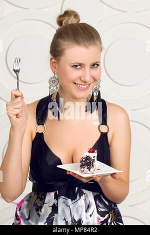 Giovane bella donna di mangiare una torta al cioccolato. Foto Stock