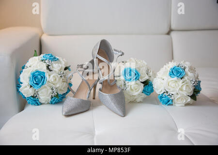 Brides giorno di nozze argento lucido scarpe con il bouquet della sposa e le sue damigelle hanno mazzi Foto Stock