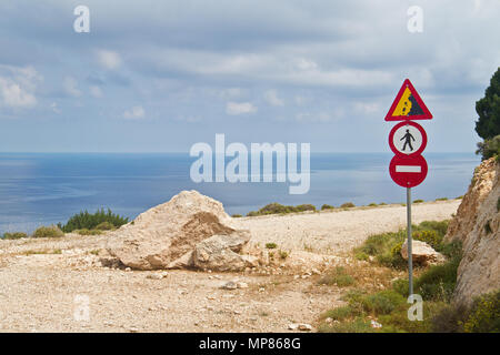 Una strada con una bellissima vista sul mare Ionico, bloccato da una roccia caduti, traffico di diversi segnali di avvertimento e il divieto di utilizzare la strada Foto Stock