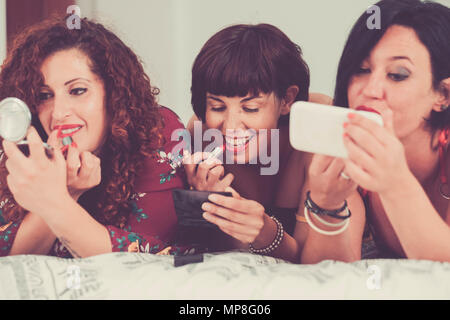 Tre femmine amici stare insieme a fissare il letto facendo fare prima di andare a fare parte della notte. amicizia concetto uno di loro ad usare un cellulare p Foto Stock