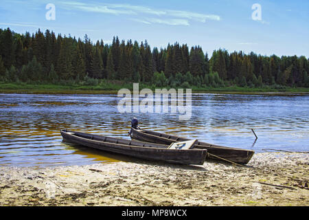 Attraccata alla riva vicino al villaggio di due lunghi classic barche in legno del Siberiano Mansi persone sul fiume North Sosva Foto Stock