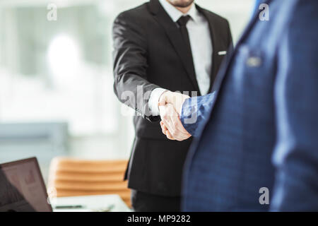 Concetto di successo nel business - stretta di mano del business partner sullo sfondo del luogo di lavoro Foto Stock