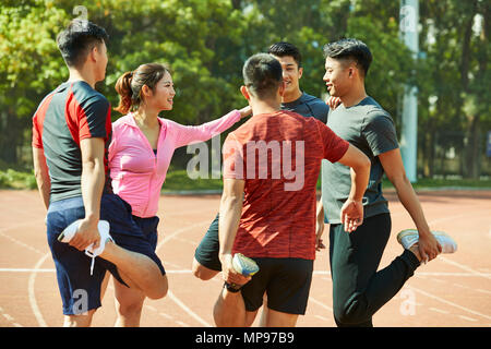 Un gruppo di giovani asiatici adulti riscaldamento stretching gambe sulla via. Foto Stock