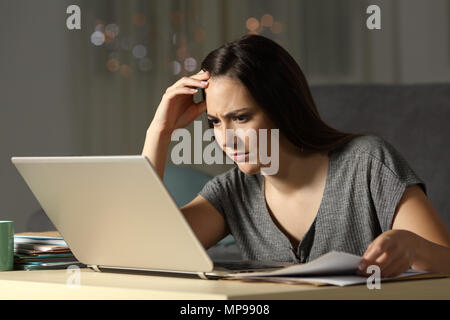 Concentrate i lavoratori autonomi lavorando online con un computer portatile nella notte a casa Foto Stock