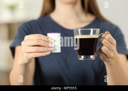 Vista frontale in prossimità di una donna mani tenendo una tazza di caffè e saccarina a casa Foto Stock