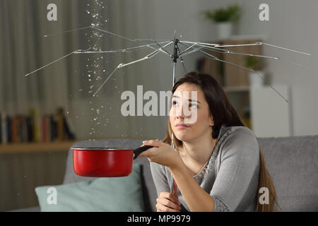 Donna che soffriva perdite di acqua a casa con un ombrello rotto. Male il concetto di assicurazione Foto Stock