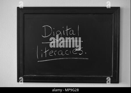 Digital literacies scritto in bianco gesso su una parete montata Blackboard. Foto Stock