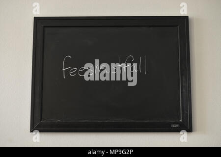 Le commissioni devono cadere scritto in bianco gesso su una parete montata Blackboard. Foto Stock