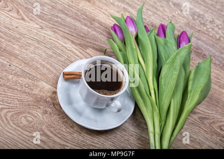 Una tazza di tè alla cannella e viola tulip su un tavolo di legno Foto Stock