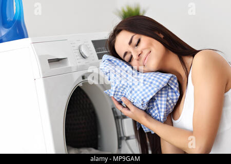 Foto di giovani casalinga con lavanderia accanto alla macchina di lavaggio Foto Stock