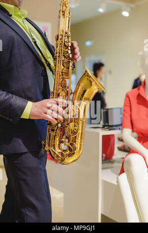 Il musicista suona il sassofono prestazioni a un concerto nel centro commerciale del negozio di abbigliamento per donna in vacanza Foto Stock