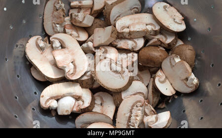 Vista dall'alto di un colapasta con fette di baby bella funghi. Foto Stock