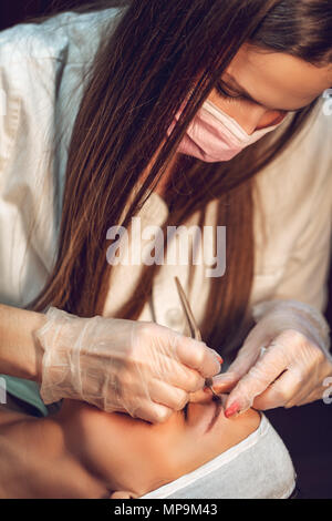 Estetista applicando il metodo giapponese del disegno sulla sopracciglia al modello. Foto Stock