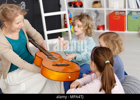 Giovane insegnante avente lezione di musica con bambini piccoli nella scuola materna Foto Stock