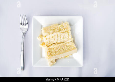 Flat Top impostazione tabella vista laici giù closeup del ristorante o un ricevimento di matrimonio bianco tovaglia tavola una piastra con crema alla vaniglia fetta di torta, forcella Foto Stock