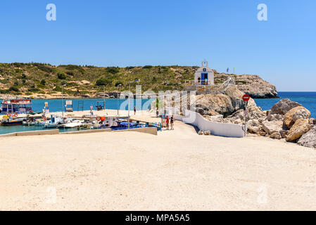 RHODES, Grecia - 12 Maggio 2017: baia con il porto per la pesca e la cappella sulle rocce in Kolymbia villaggio sull'isola di Rodi. La Grecia Foto Stock