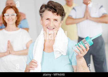 Felice active donna anziana tenendo la bottiglia di acqua Foto Stock