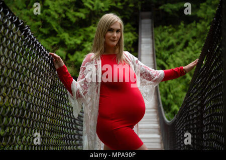 Giovane donna caucasica con un ventre pregrant nella natura. Prese a Lynn Valley, North Vancouver, BC, Canada. Foto Stock