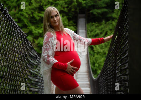 Giovane donna caucasica con un ventre pregrant nella natura. Prese a Lynn Valley, North Vancouver, BC, Canada. Foto Stock