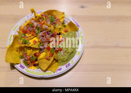 Deliziosa scorpacciata di nachos con formaggio e Guacamole su legno Foto Stock