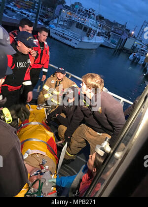 Coast Guard Sottufficiali di terza classe Manny Groll, Kyle Crabtree e Spencer Kelly, il suo equipaggio alla Stazione della Guardia Costiera Little Creek in Virginia Beach, Virginia, stand-by per assistere EMS locale come prendersi cura di un uomo sofferente a bordo della stazione a 45 piedi Boat-Medium risposta a ingresso Rudee in Virginia Beach, Aprile 7, 2017. L'uomo è stato colpito da arresto respiratorio a bordo della nave da crociera la grandezza dei mari quando la nave di crociera personale richiedeva un Coast Guard medevac. Foto Stock