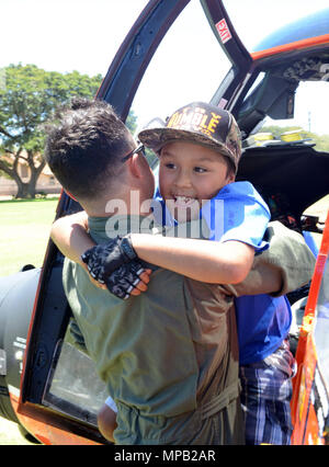 Petty Officer di 2a classe di Casey Allan, aviazione un tecnico di manutenzione dalla guardia costiera Stazione aria Barbieri punto, Oahu, aiuta a 12-anno-vecchio Felix Kehano in un MH-65 Delfino elicottero durante un evento D.A.R.E. per Kualapuu carta pubblica la scuola dei bambini a Kaunakakai Ball Park, Molokai, Aprile 7, 2016. Il rally si è tenuta a informare i bambini sui pericoli della droga e comprendeva anche dimostrazioni da parte della guardia costiera Stazione aria Barbieri punto, Guardia nazionale, Maui il dipartimento di polizia della contea di Maui Vigili del Fuoco, Hawaii Dipartimento della Terra e delle risorse naturali e numerose altre agenzie. Foto Stock