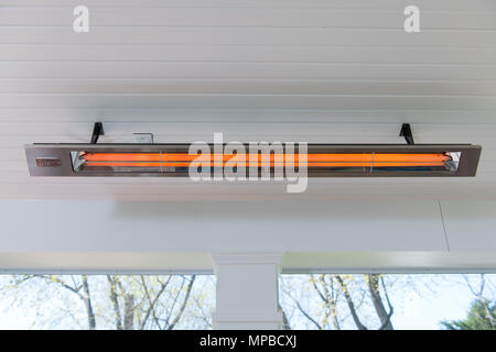 Un elettrico riscaldatore a raggi infrarossi su una veranda riparata fornisce il calore radiante nelle giornate fredde Foto Stock