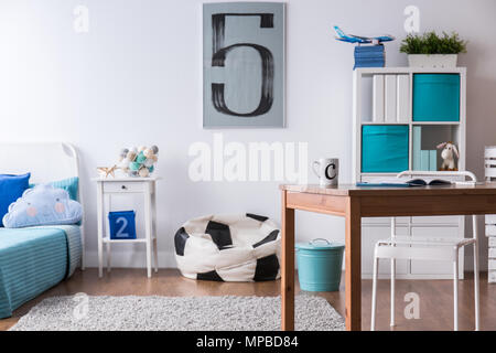 Elegante ragazzo in camera con scrivania in legno e cuscino in calcio forma  a sfera Foto stock - Alamy