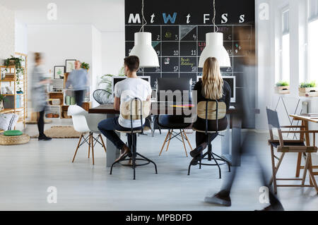 Persone in moderno spazio coworking con blackboard calendario Foto Stock